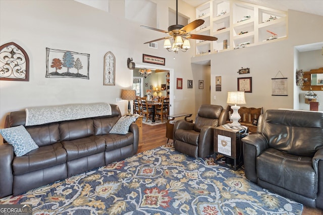 living area with a ceiling fan, a high ceiling, and wood finished floors