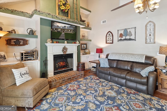 living area with a high ceiling, dark wood-style flooring, a brick fireplace, and visible vents