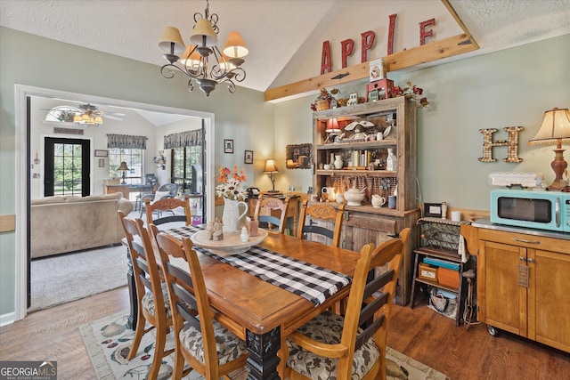 dining area with lofted ceiling, a textured ceiling, ceiling fan with notable chandelier, and wood finished floors