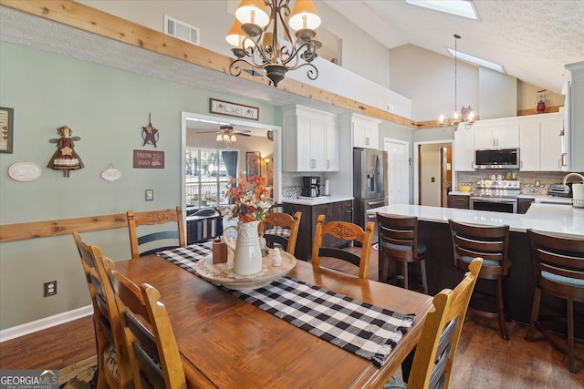 dining area with dark wood-style floors, visible vents, a textured ceiling, and ceiling fan with notable chandelier