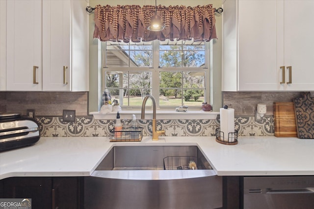 kitchen featuring light countertops, stainless steel dishwasher, and backsplash