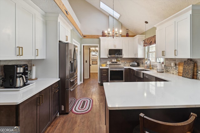 kitchen with dark wood-style flooring, a sink, white cabinetry, appliances with stainless steel finishes, and lofted ceiling with skylight