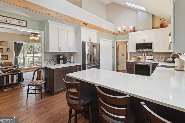 kitchen with light countertops, appliances with stainless steel finishes, dark wood-style flooring, and a sink