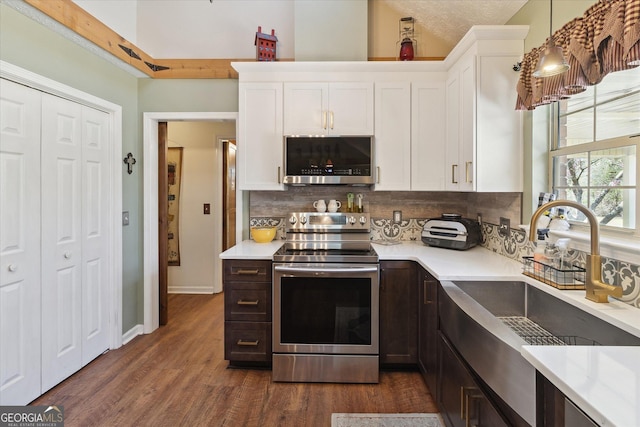 kitchen with backsplash, white cabinetry, stainless steel appliances, and light countertops