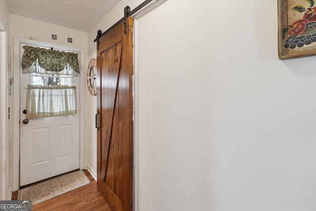 entryway featuring wood finished floors, a textured ceiling, and a barn door
