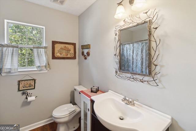 full bath with toilet, visible vents, baseboards, and vanity