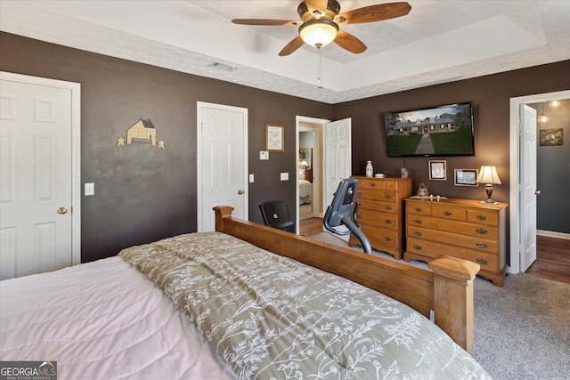 bedroom featuring ceiling fan, carpet, a raised ceiling, and visible vents