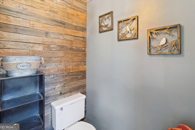 bathroom featuring toilet and wood walls