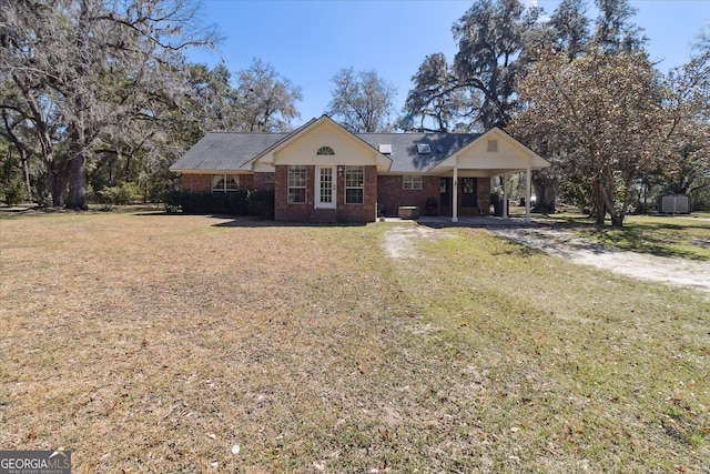 view of front of property featuring driveway, a front yard, an attached carport, and brick siding