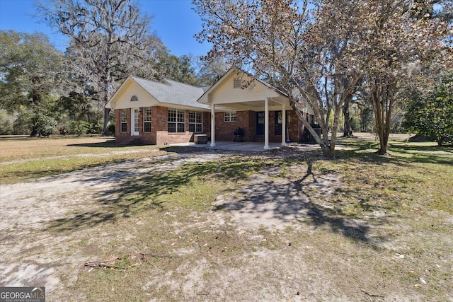 view of front facade with a patio area, a front yard, and brick siding