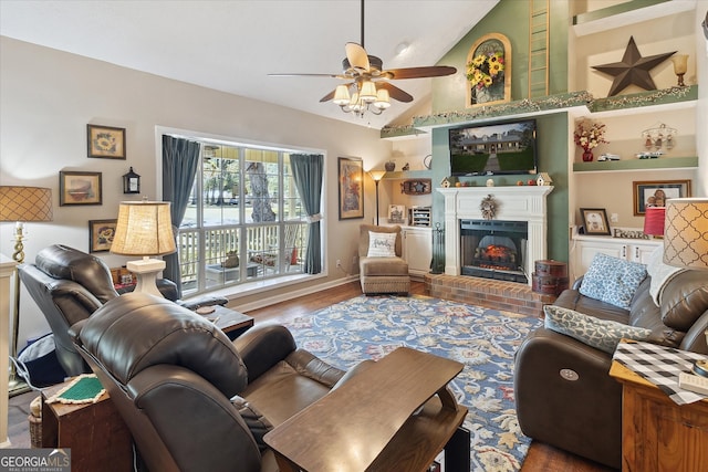 living area with lofted ceiling, built in shelves, a fireplace, wood finished floors, and a ceiling fan