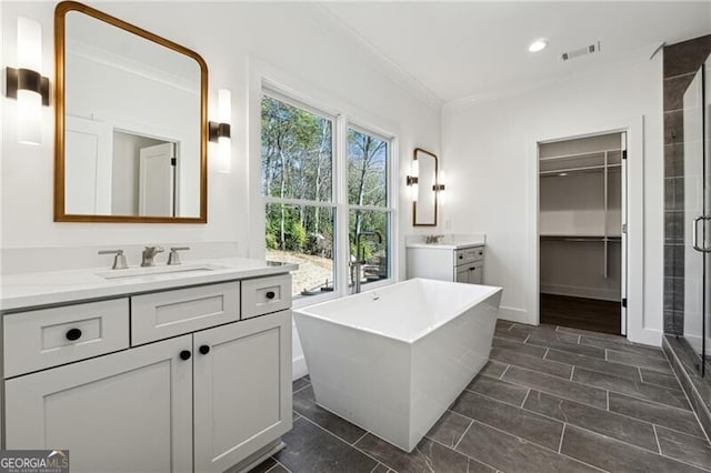 bathroom with a freestanding tub, two vanities, a stall shower, a sink, and crown molding