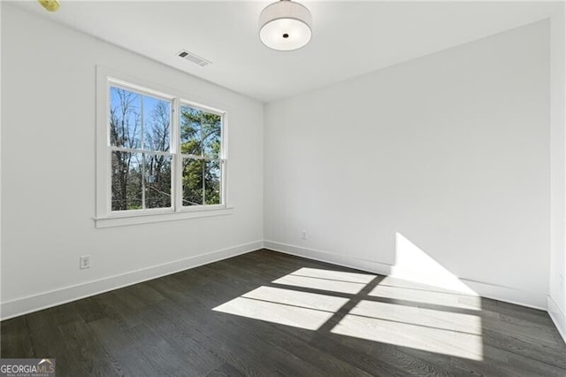 spare room with visible vents, baseboards, and dark wood finished floors