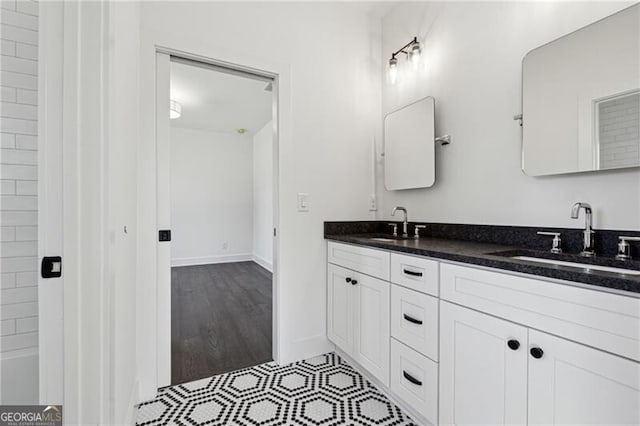 bathroom featuring double vanity, baseboards, and a sink