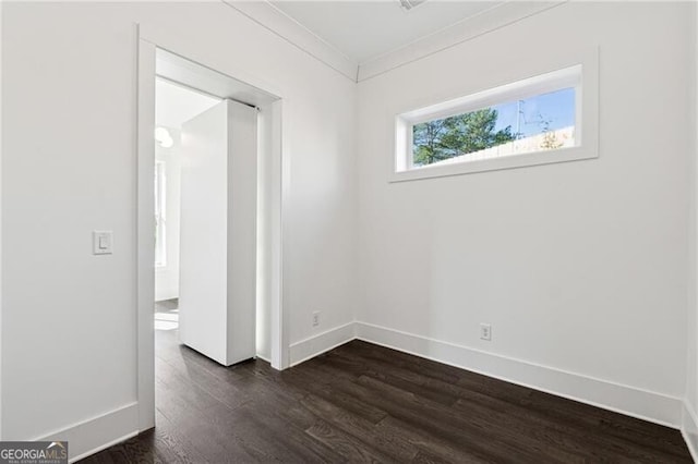 spare room with baseboards, dark wood finished floors, and crown molding