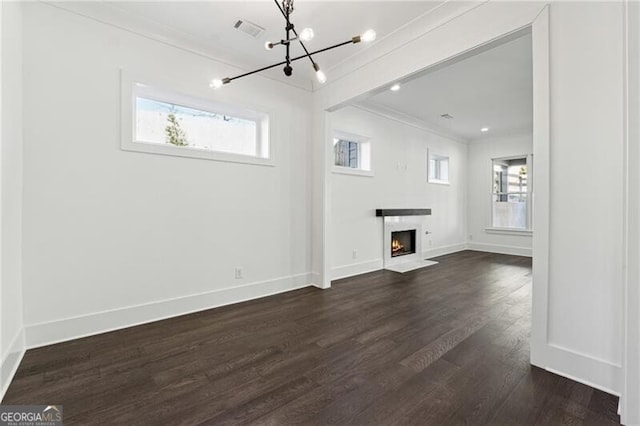 unfurnished living room featuring a fireplace with flush hearth, visible vents, a wealth of natural light, and ornamental molding