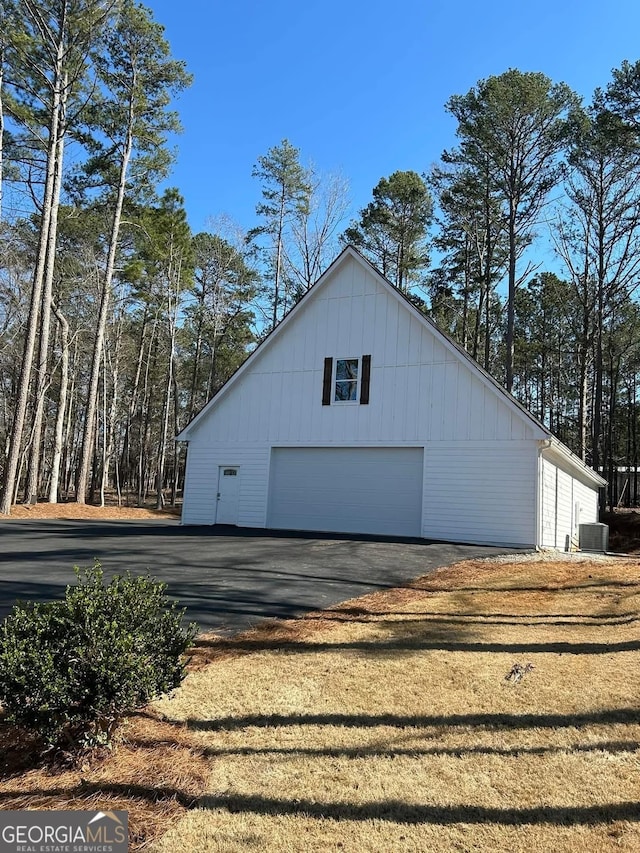 view of side of home with a detached garage, central AC unit, and an outdoor structure