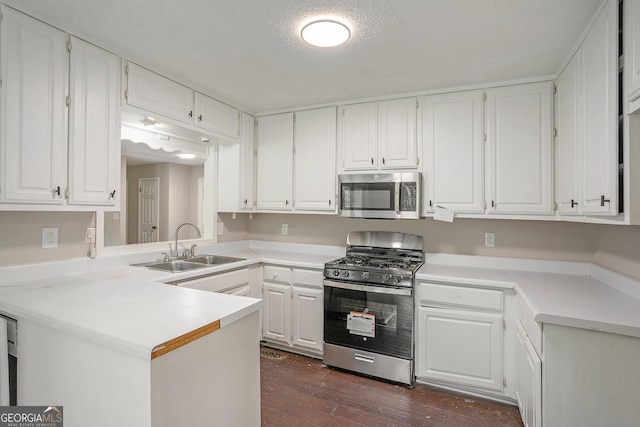 kitchen with dark wood finished floors, light countertops, appliances with stainless steel finishes, white cabinetry, and a sink