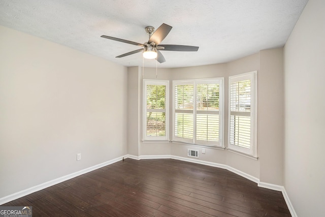 spare room featuring a textured ceiling, dark wood-style floors, visible vents, and baseboards