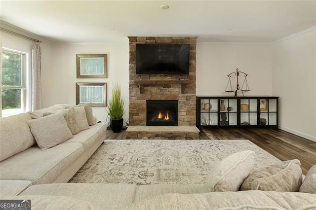 living area featuring a stone fireplace, crown molding, wood finished floors, and baseboards