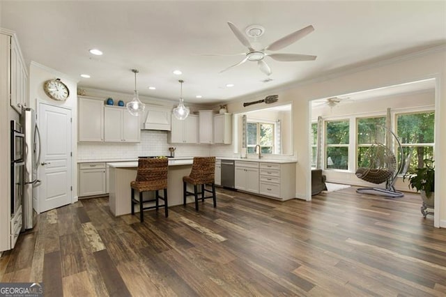 kitchen featuring a kitchen island, crown molding, dark wood finished floors, dishwasher, and custom range hood