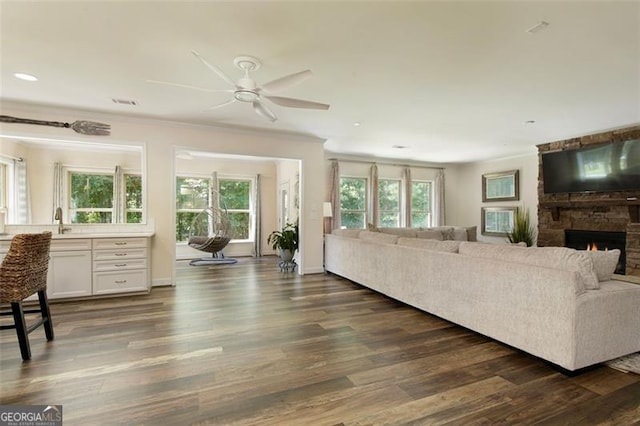 living room featuring crown molding, plenty of natural light, and dark wood-style flooring