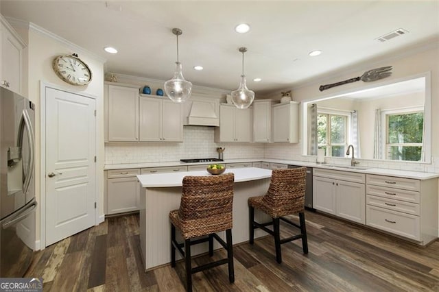 kitchen with a center island, crown molding, stainless steel refrigerator with ice dispenser, custom exhaust hood, and gas cooktop