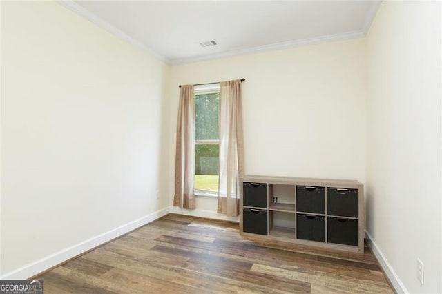 unfurnished bedroom featuring visible vents, wood finished floors, baseboards, and ornamental molding