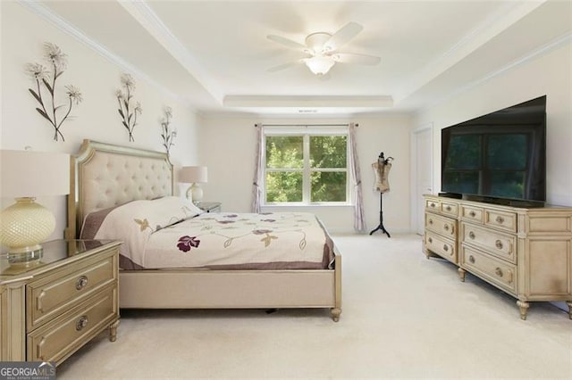 bedroom featuring a ceiling fan, a raised ceiling, light colored carpet, and ornamental molding