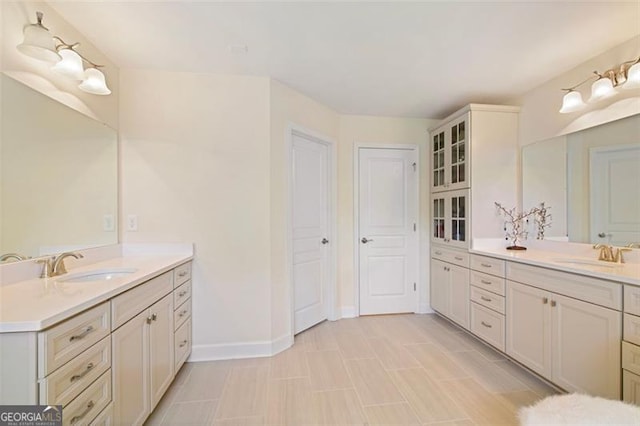 full bath with two vanities, baseboards, and a sink