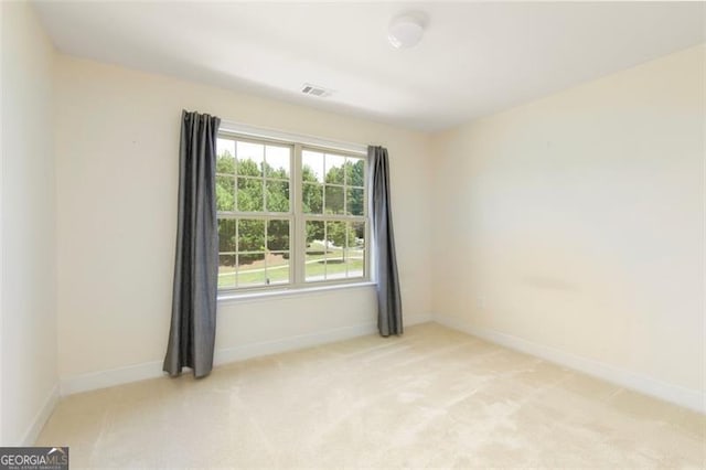 spare room featuring visible vents, baseboards, and light colored carpet