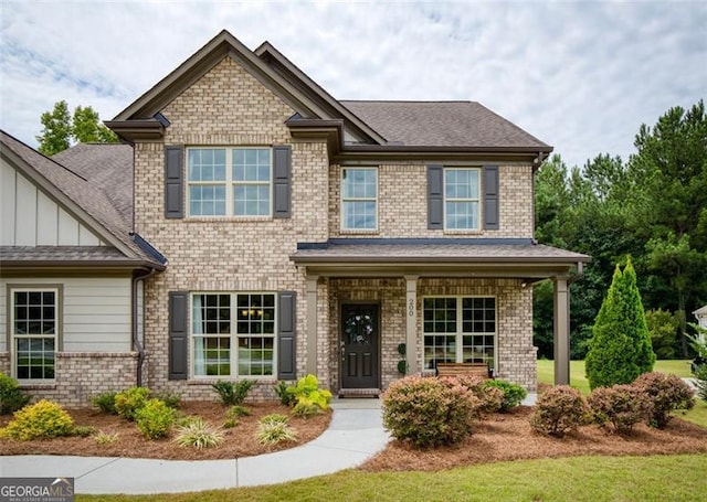 craftsman house with brick siding, board and batten siding, a porch, and roof with shingles