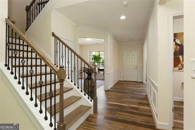 foyer with dark wood finished floors, recessed lighting, wainscoting, a decorative wall, and crown molding