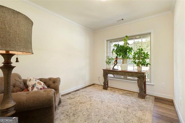 sitting room featuring baseboards, wood finished floors, visible vents, and ornamental molding