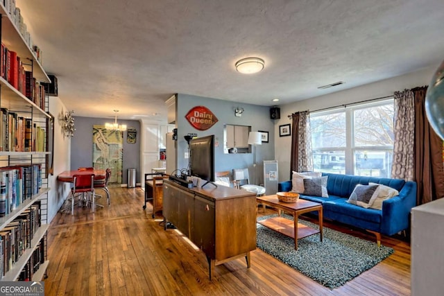 interior space with a chandelier, wood-type flooring, and visible vents