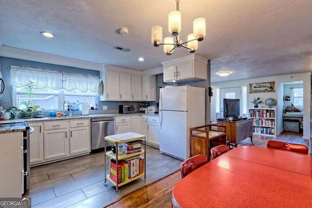 kitchen featuring visible vents, white cabinetry, hanging light fixtures, stainless steel dishwasher, and freestanding refrigerator