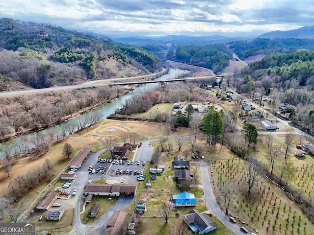 aerial view with a water and mountain view and a wooded view