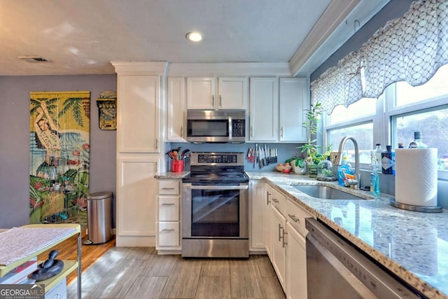 kitchen featuring stainless steel appliances, light wood finished floors, a sink, and white cabinets