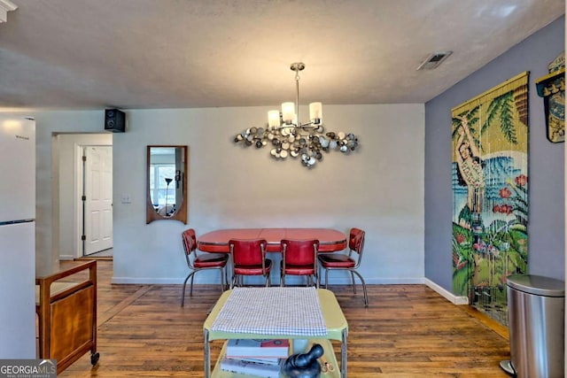 dining space with visible vents, baseboards, a chandelier, and wood finished floors