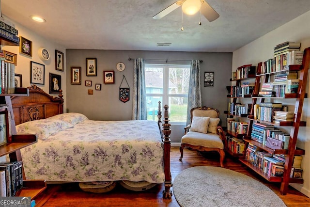 bedroom with baseboards, ceiling fan, visible vents, and wood finished floors