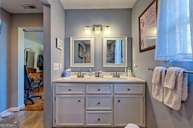 bathroom featuring double vanity, visible vents, a sink, and wood finished floors