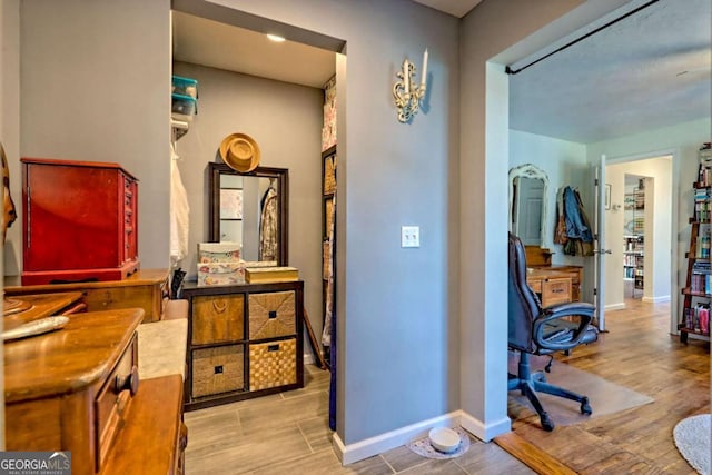 corridor featuring baseboards and wood finished floors