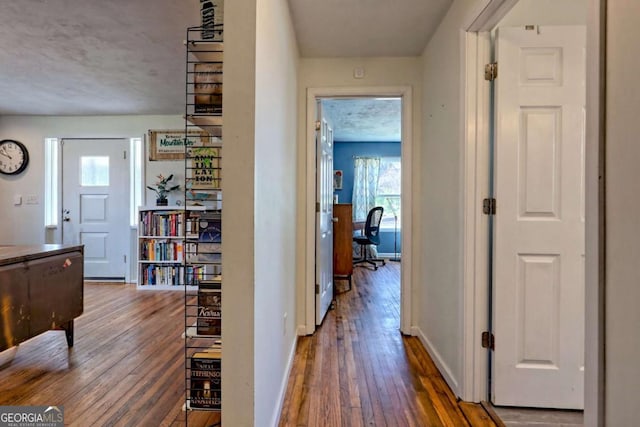 hallway featuring wood-type flooring and baseboards