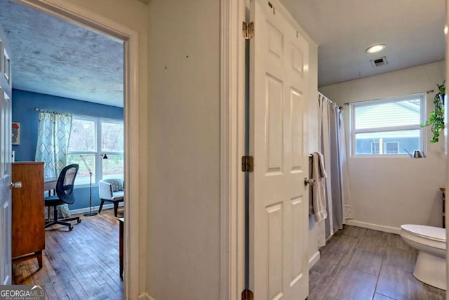 full bathroom with visible vents, plenty of natural light, toilet, and baseboards