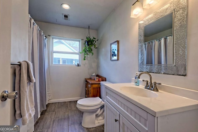 full bath with baseboards, visible vents, toilet, vanity, and wood finish floors