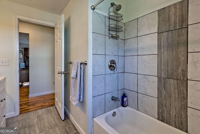 bathroom featuring washtub / shower combination, baseboards, and vanity