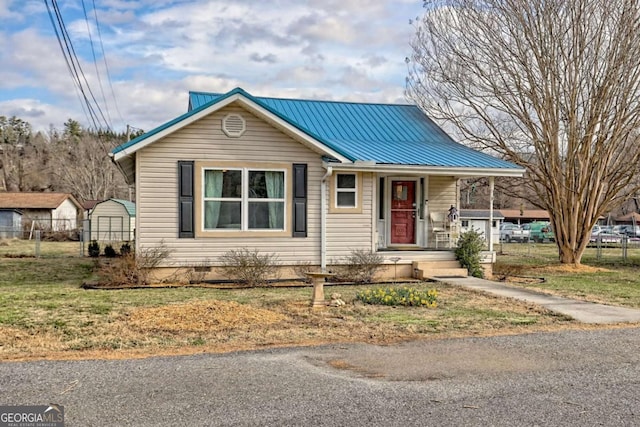 view of front of house with a porch, metal roof, and fence