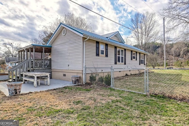 view of side of home with metal roof, fence, crawl space, a lawn, and a patio area