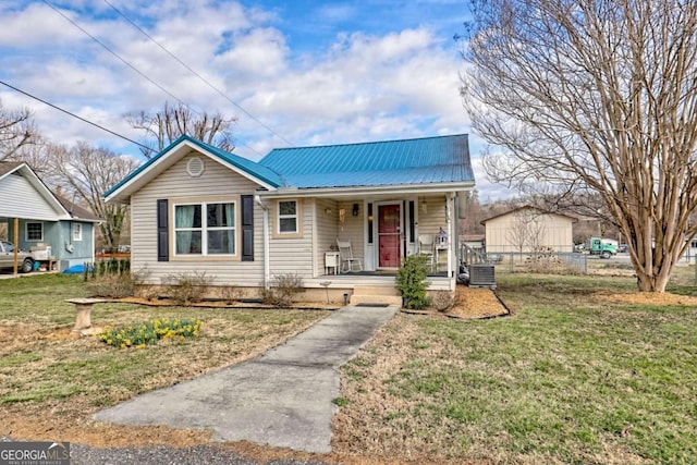 view of front of property featuring metal roof, a porch, central air condition unit, fence, and a front yard