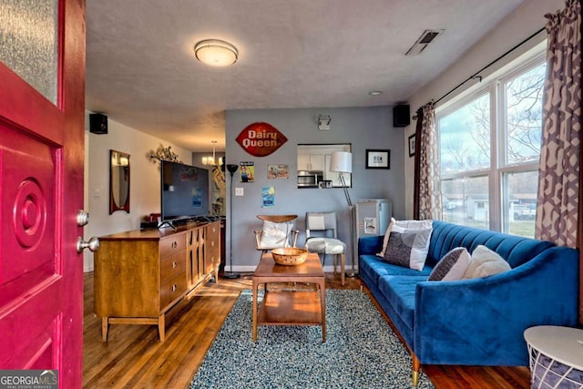 living room featuring visible vents, baseboards, and wood finished floors